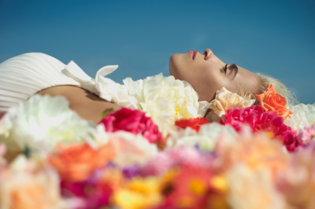 Beautiful blonde young woman lying in flowers